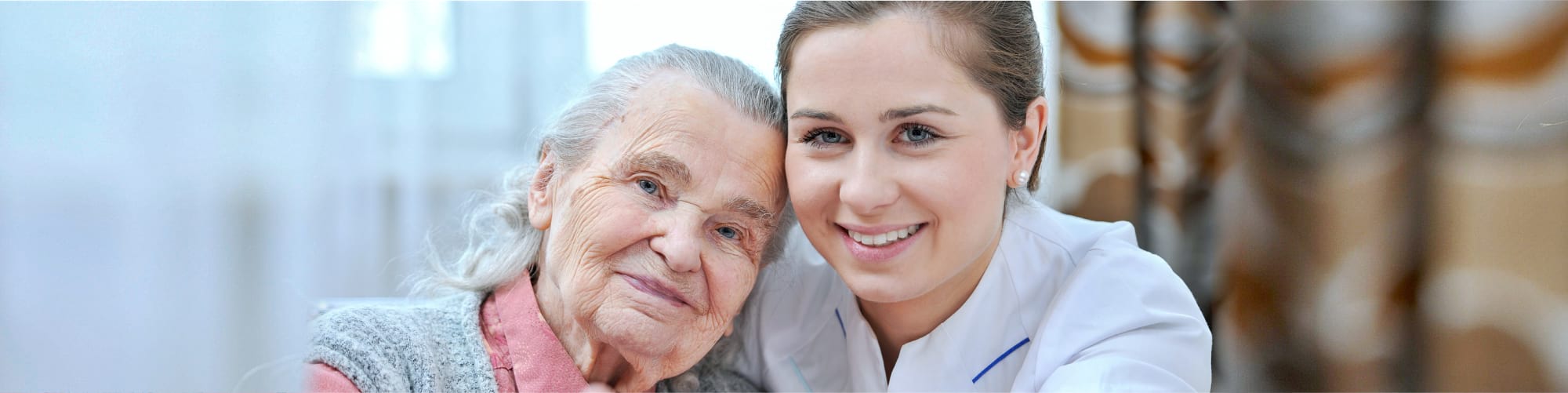 senior and caregiver smiling each other